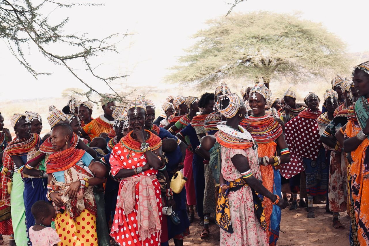 Vibrant gathering of African women in traditional attire celebrating outdoors.
