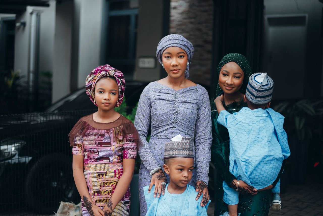 A group of Nigerian siblings in vibrant traditional clothing posing outdoors, showcasing cultural fashion.